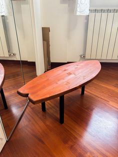 a wooden surfboard sitting on top of a hard wood floor next to a mirror