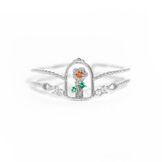 a white gold ring with an orange and green stone in the shape of a cross