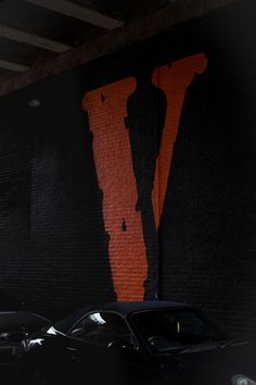 two cars parked in front of a wall with an orange and black design on it