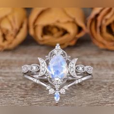 an engagement ring with a pear shaped blue topazte surrounded by diamonds and roses