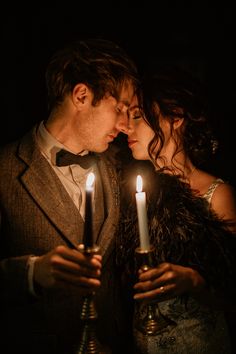 a man and woman are kissing with candles in front of their faces as they stand close to each other