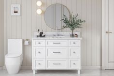 a bathroom with a toilet, mirror and plant on the counter top in front of it