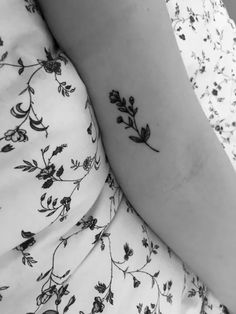 a black and white photo of a woman's arm with small flowers on it