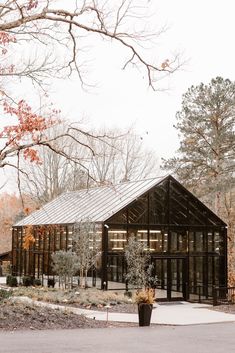 a wooden building surrounded by lots of trees and bushes in the fall time with leaves on the ground