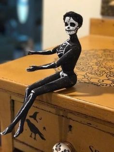 a skeleton figurine sitting on top of a wooden table next to a drawer