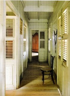 an empty hallway with shutters on both sides and a bench in the middle between