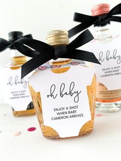 three baby shower favors in small bottles with black ribbons on them and one is empty