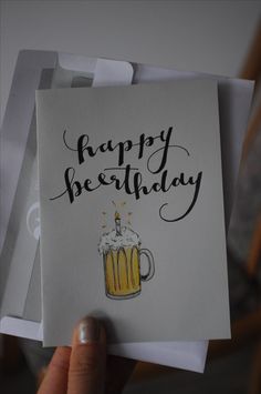 a person holding up a birthday card with a beer mug on it and the words happy birthday written in black ink