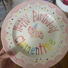 a person holding up a plate with the words happy birthday clementine written on it