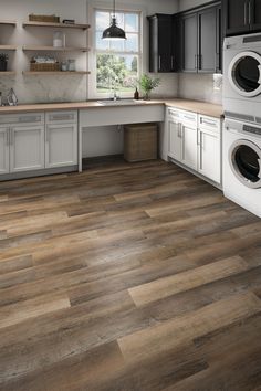 a kitchen with white cabinets and wood floors is shown in this image, there is a washer and dryer on the counter