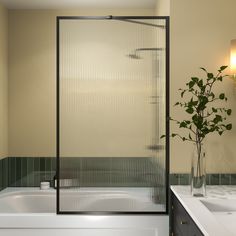 a white bath tub sitting next to a sink under a bathroom mirror with lights on it