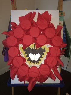 an art work made out of red paper with a batman symbol on it's face