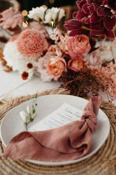 a place setting with pink flowers and napkins on the plate, along with an empty menu