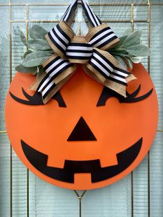 a pumpkin shaped door hanger with a bow on it