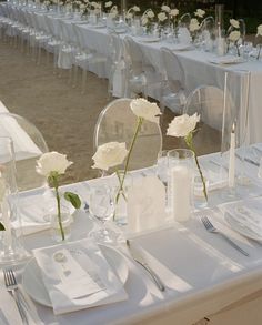 the table is set with white flowers and place settings