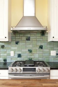 a stove top oven sitting inside of a kitchen next to white cabinets and wooden floors