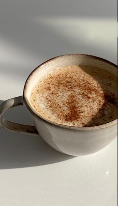 a cup of coffee sitting on top of a white table