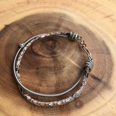 two silver bracelets sitting on top of a wooden table