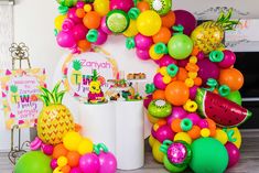 there are many balloons and fruits on the table together in this party decoration set up