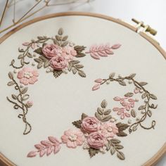 a close up of a embroidery on a white cloth with pink flowers in the middle