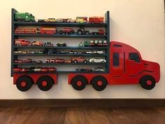 a red toy truck is mounted to a wall with shelves filled with cars and trucks