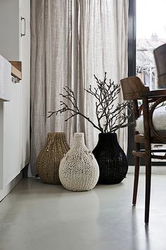 three vases are sitting on the floor in front of a window with drapes