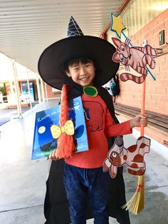 a young boy dressed up as a witch holding a broom and book in his hand