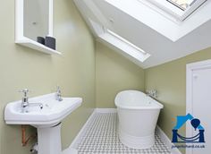 a white bath tub sitting under a skylight next to a sink and toilet in a bathroom