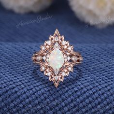 a white opal and diamond ring sitting on top of a blue blanket