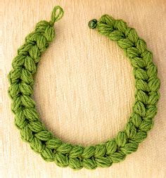 a close up of a green bracelet on a wooden surface with a knot in the middle