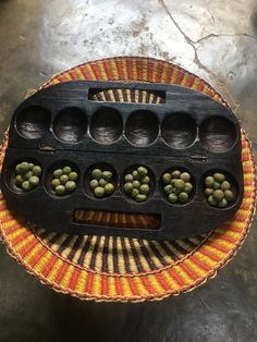 a wooden tray with green peas in it on top of a woven tablecloth covered surface