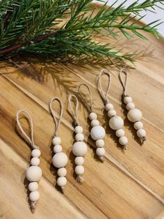 three wooden beads are hanging from a tree branch on a cutting board with pine needles