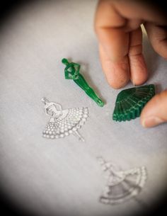 a hand is touching some plastic objects on a sheet of white paper with green trim