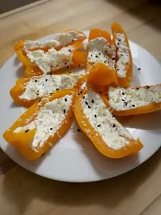 slices of oranges with cheese and black pepper on a white plate sitting on a wooden table