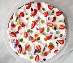 a white plate topped with a cake covered in whipped cream and fruit toppings on top of it