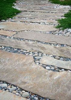 a stone path with rocks and grass on either side