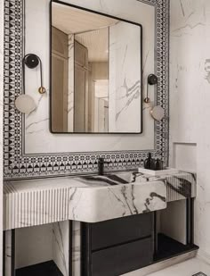 a bathroom with marble counter tops and black accents on the walls, along with a large mirror