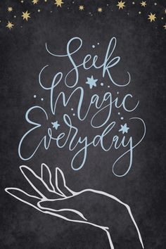 a hand holding the words seek magic everyday on a chalkboard background with gold stars