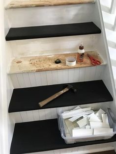 some black and white shelves with tools on them next to the stairs in a house