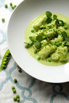 a white bowl filled with peas and green sauce