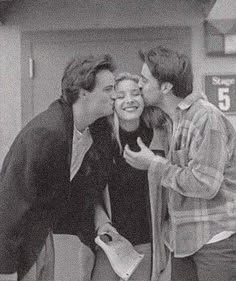 three young men and one woman kissing in front of a gas station sign while the man is holding his mouth open