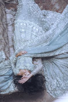 a woman is laying on the ground in a silver dress with sequins and beads