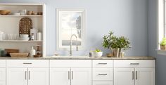 a kitchen with white cabinets and purple walls