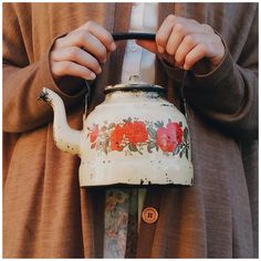 a person holding a tea pot with flowers painted on it and the words russian above them