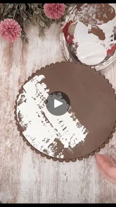 someone is cutting into a cake with white frosting and brown icing on it