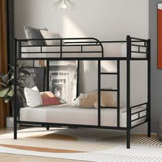 a black metal bunk bed sitting on top of a wooden floor next to a window