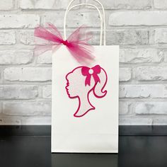 a paper bag with a silhouette of a woman's head and pink bow on it