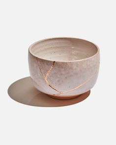 a white bowl sitting on top of a table next to a brown plate with gold trim