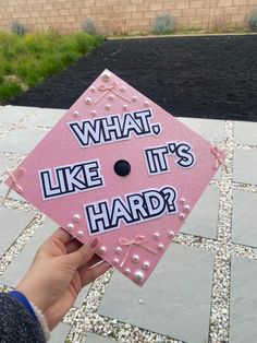 a pink graduation cap that says what, like it's hard?