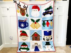 a christmas quilt hanging on the wall in front of a white door with snowmen, santa